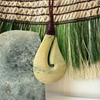 pounamu greenStone hook pendant on a woven grass Harakeke Kakahu background