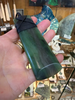 X Large green stone pounamu jade  pendant with a black cord against a store display background